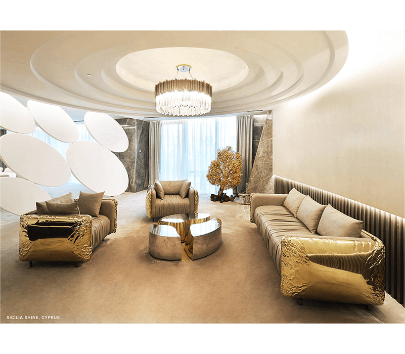 Luxurious living room with gold couch, love seat, and chair illuminated by a circular crystal light.